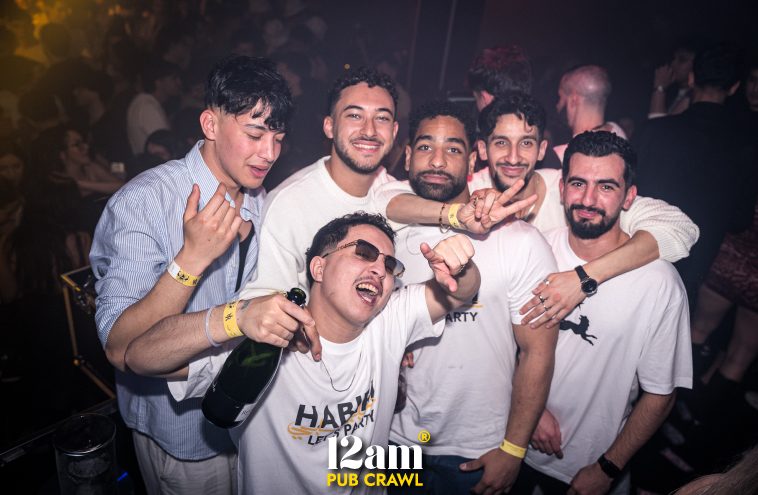Group of happy young adults, including Erasmus students and solo travelers, posing with one of the founders of MOOR Club during a 12am Pub Crawl in Madrid, showcasing exclusive nightlife access.