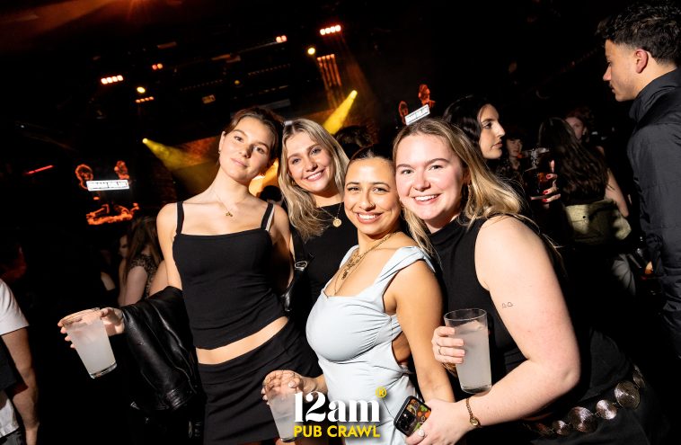 Group of happy Erasmus students and solo travelers holding drinks and smiling inside a lively Madrid club during a 12am Pub Crawl. Showcasing the fun, vibrant atmosphere, and new connections on a pub crawl in Madrid.