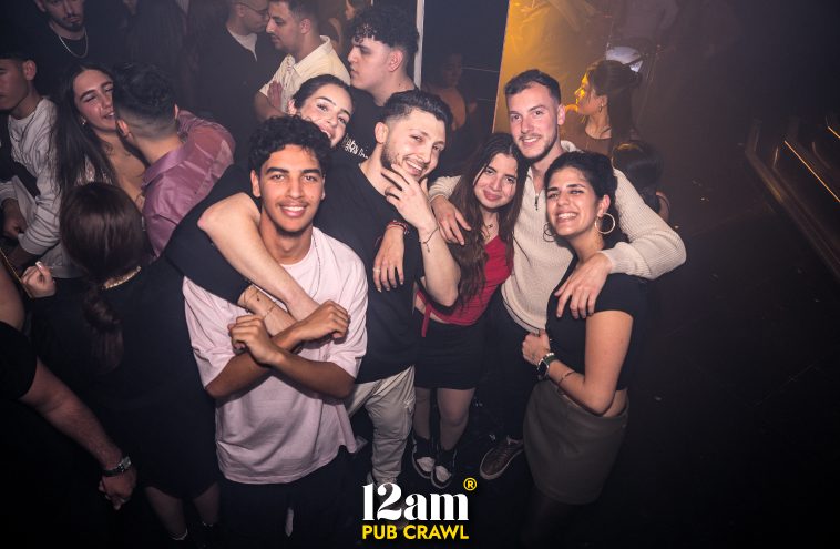 Group of happy young adults, including Erasmus students and solo travelers, enjoying a Halloween-themed Madrid pub crawl with the 12am Pub Crawl. Capturing the festive nightlife in Madrid.