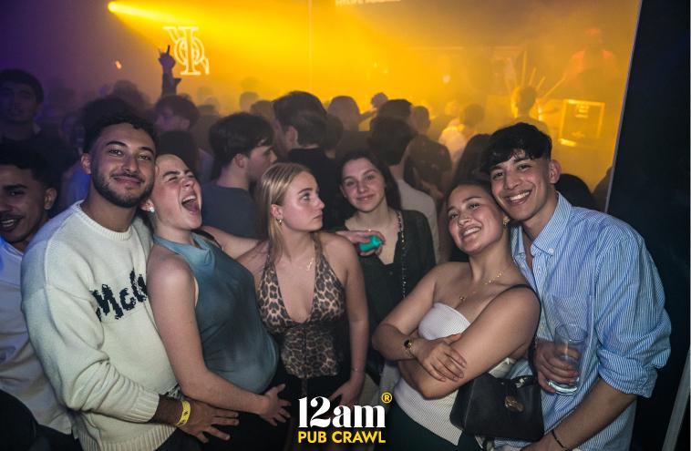 Diverse group of happy young adults, including Erasmus students and solo travelers, enjoying an Arabian night themed event at ICON Madrid Club during a 12am Pub Crawl. Showcasing unique Madrid nightlife experiences.